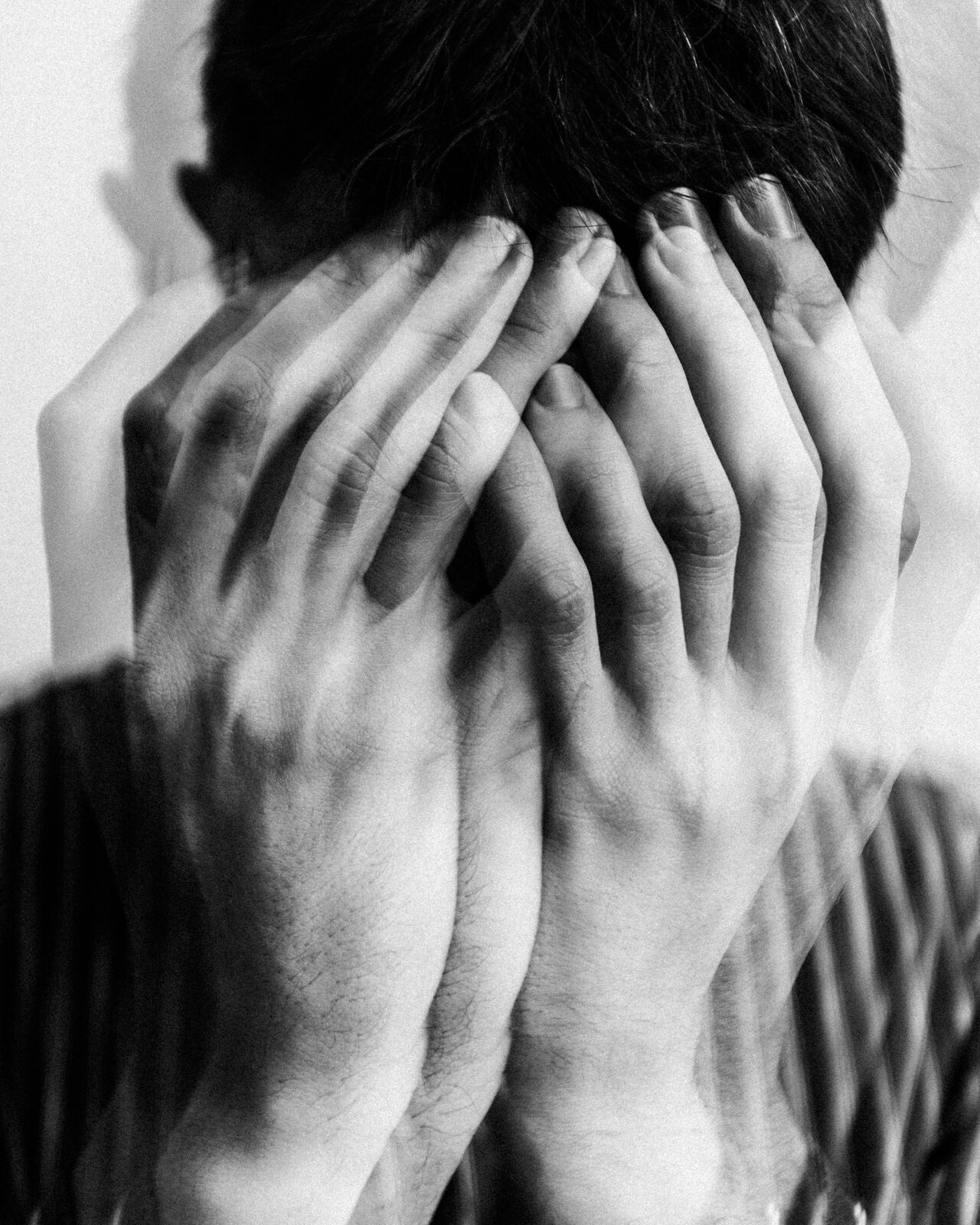 Hands covering a face, layered in double exposure