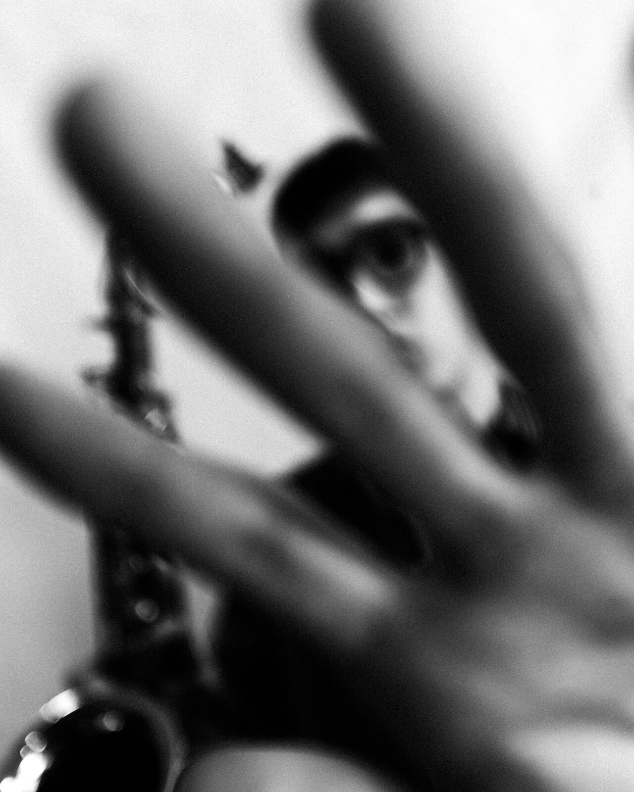 Blurred hand in the foreground with one eye in focus behind it