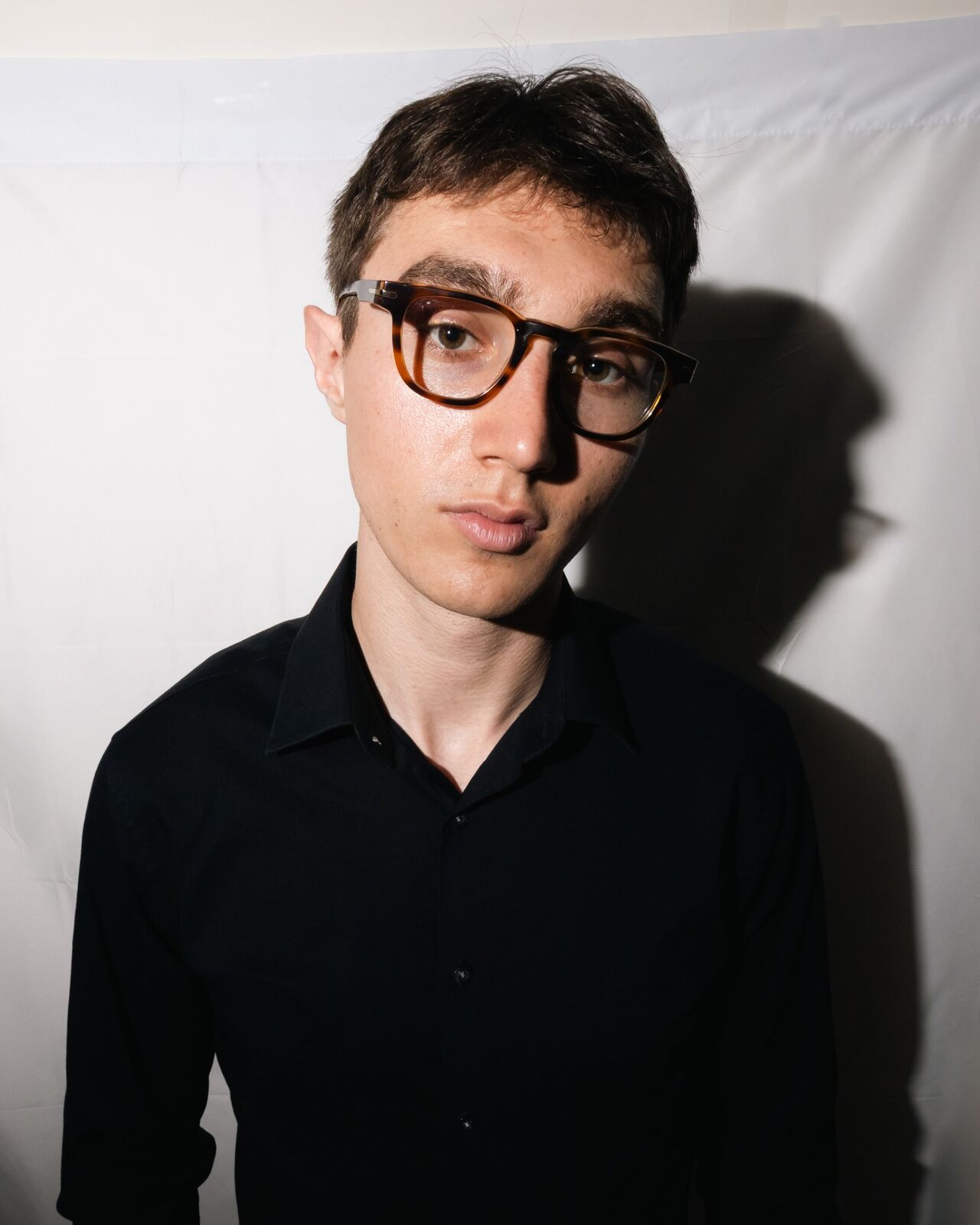 Portrait in tortoiseshell glasses against a white backdrop
